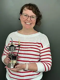 Raina Telgemeier, ganadora del premio Inkpot en el 2023, mostrando el diseño actual del trofeo.