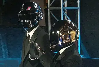 Dos hombres que llevan ropa gris y cascos de robot.