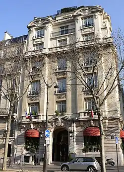 A six storey building at the corner of a terrace lined in front by bare trees